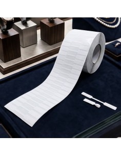 Rollo de etiquetas adhesivas para joyería junto a la muestra de etiqueta en su formato abierto y cerrado